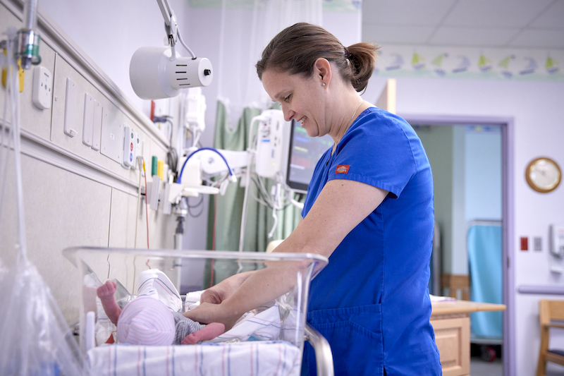 A nurse examining a baby in NICU