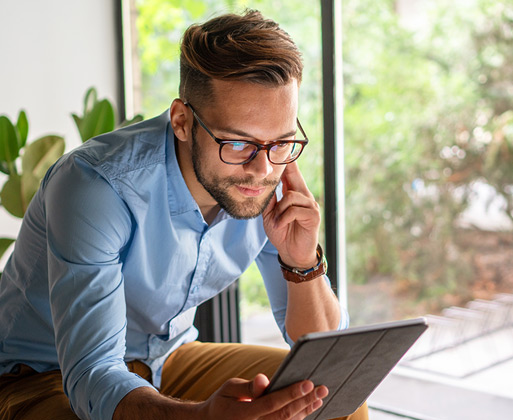 A guy in glasses looking over his computer while on the phone