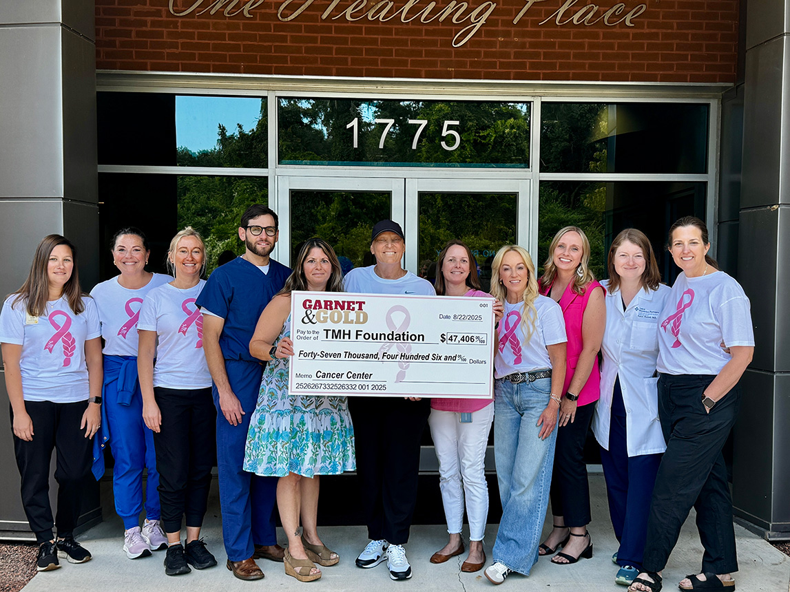 Garnet & Gold and TMH Foundation members stand with a Check