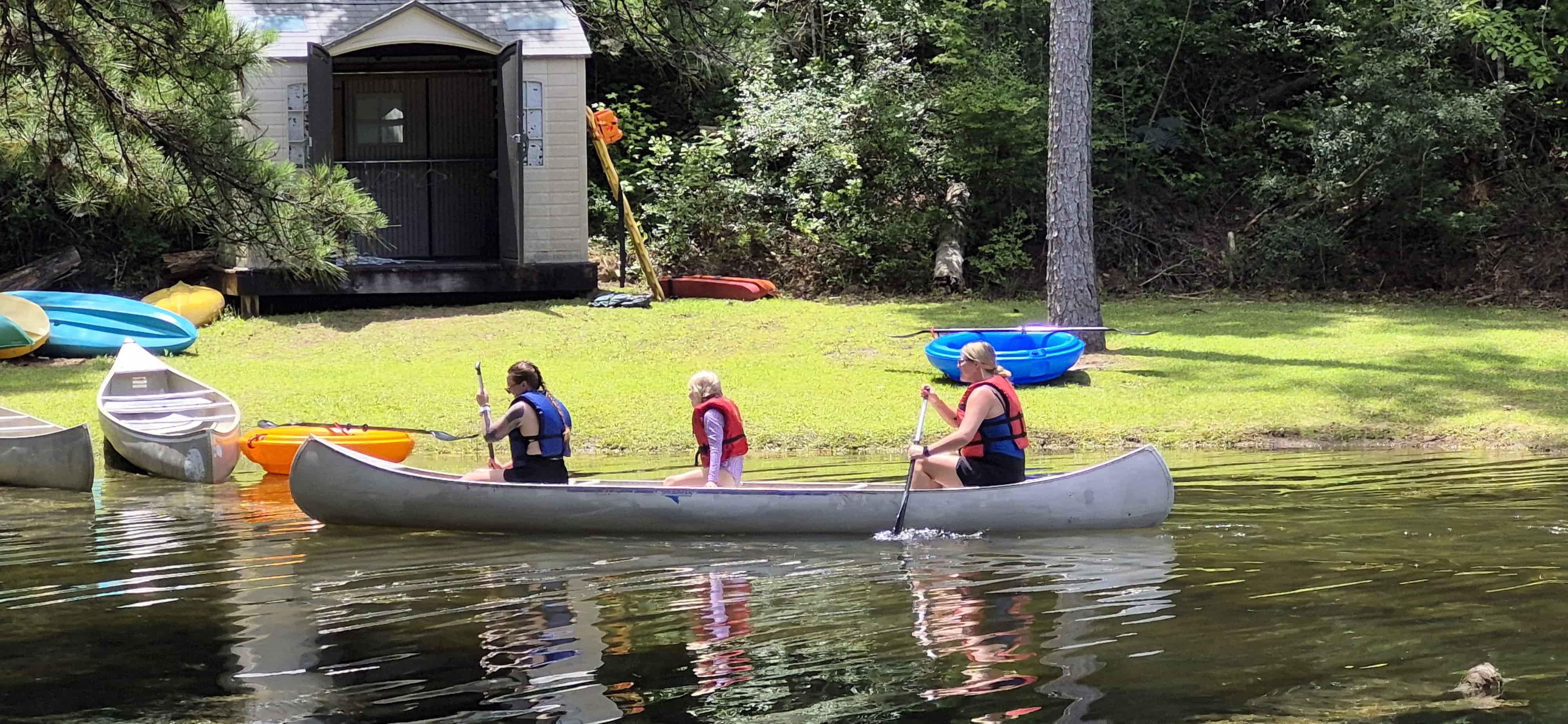 Three children paddle a canoe across a lake at Florida Diabetes Camp.