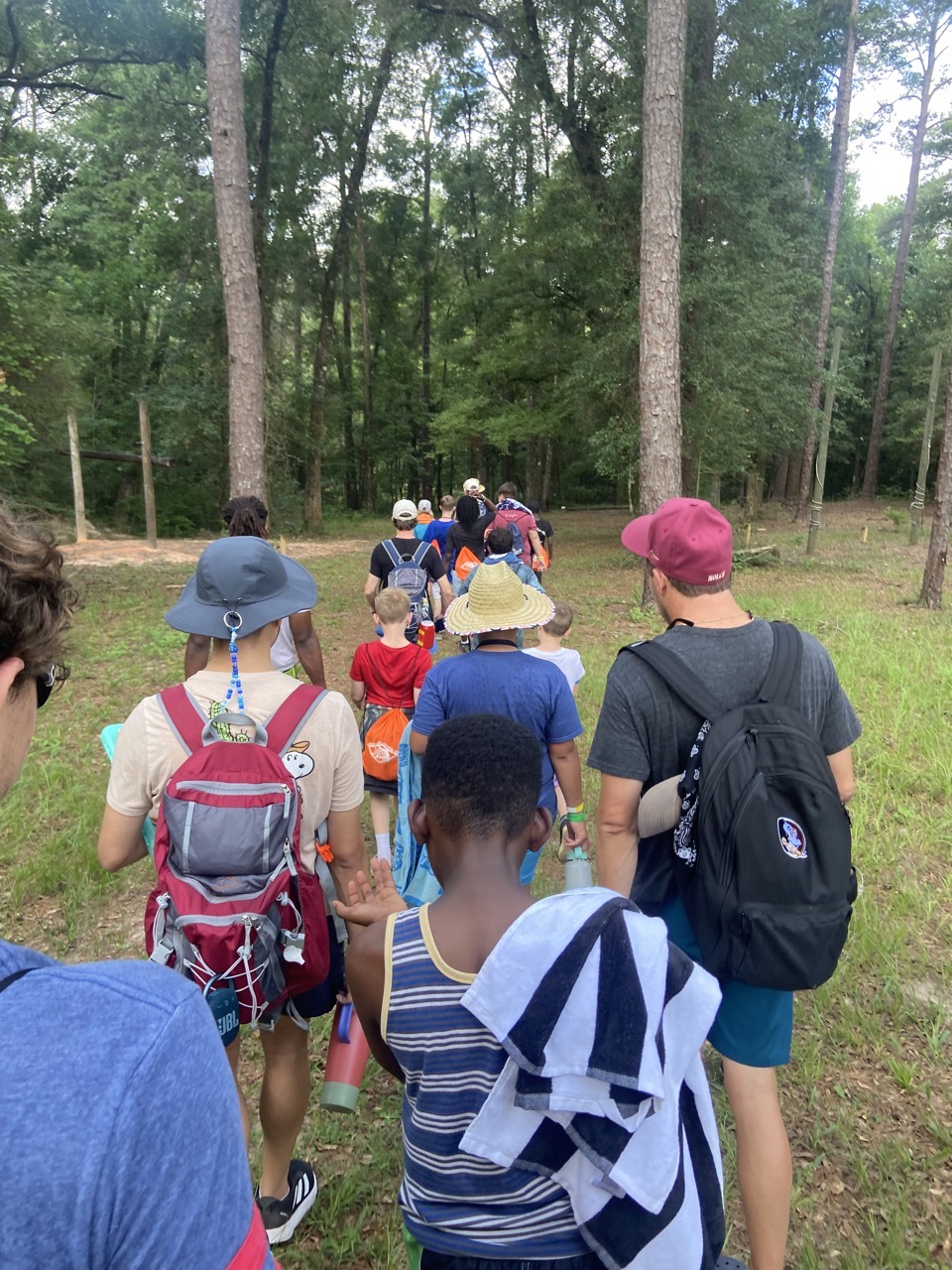Campers and counselors head out on a wooded trail.