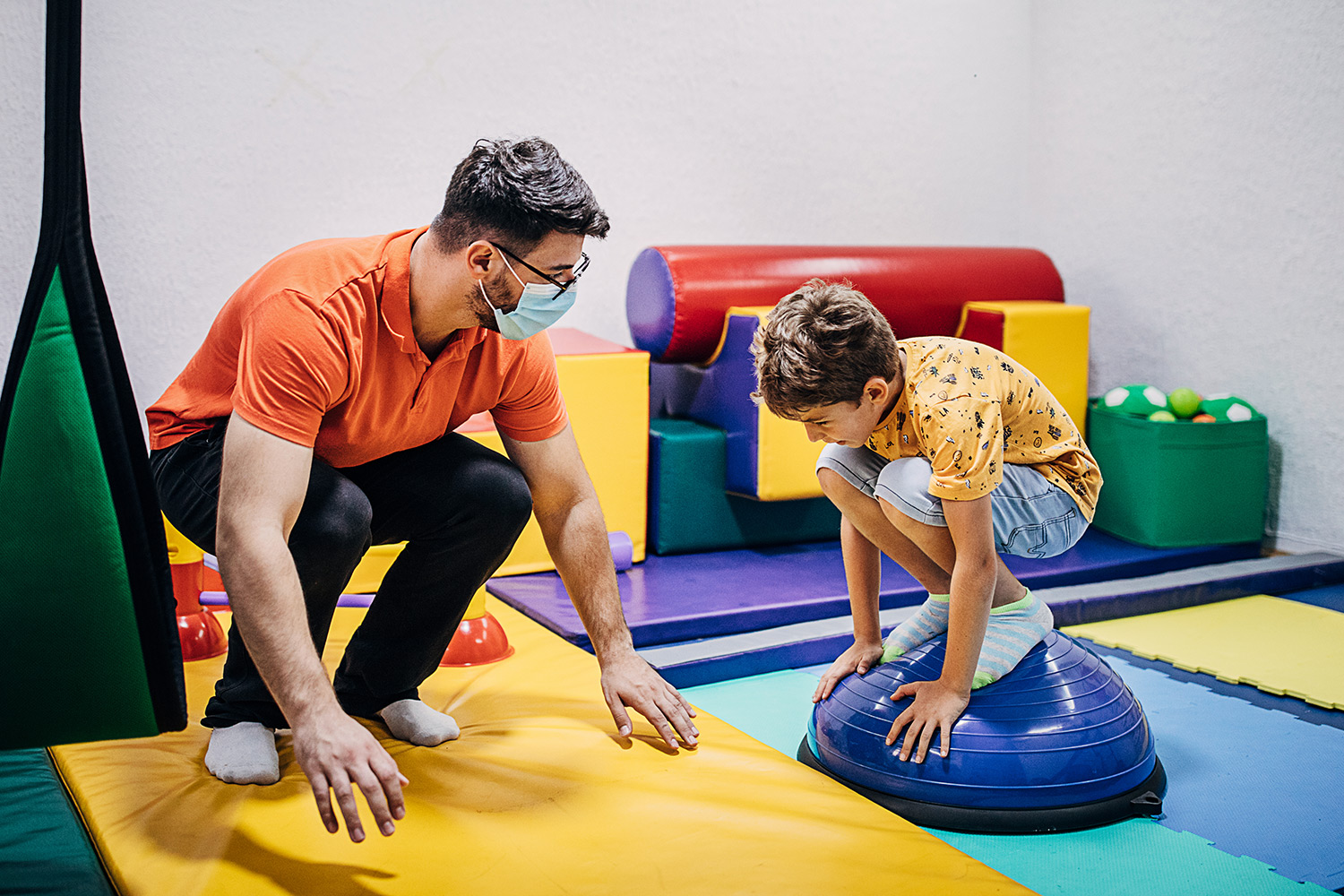 A pediatric specialist helping a child exercise.