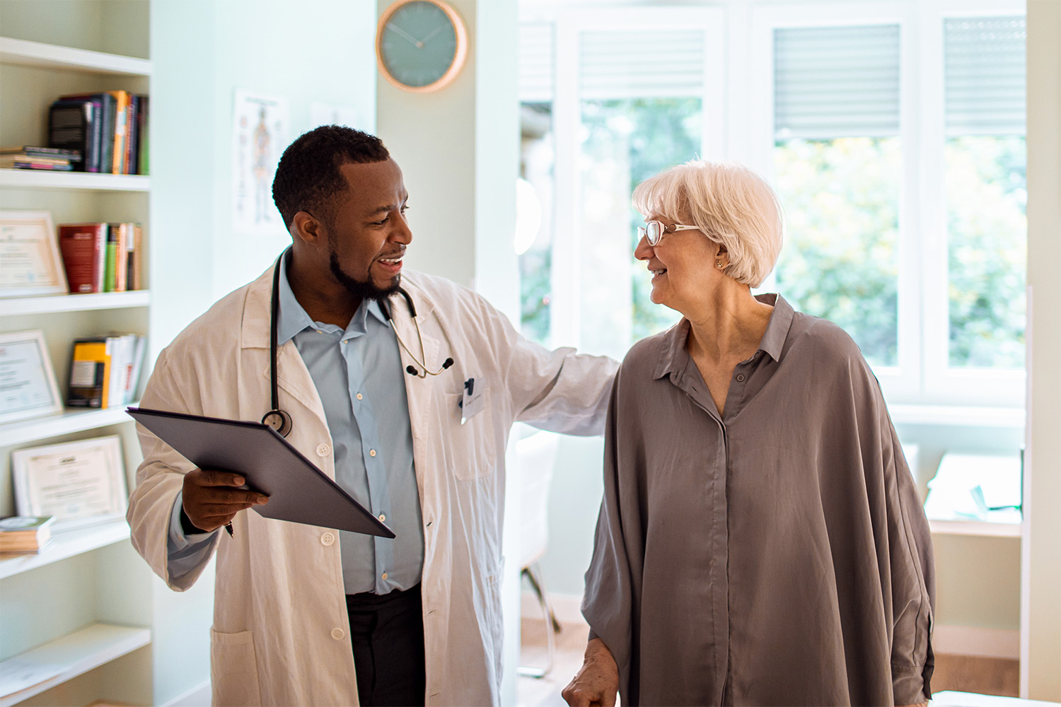 A physician speaking with his hand on his patient's back