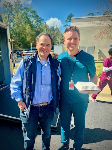 Two men pose for a photo outside